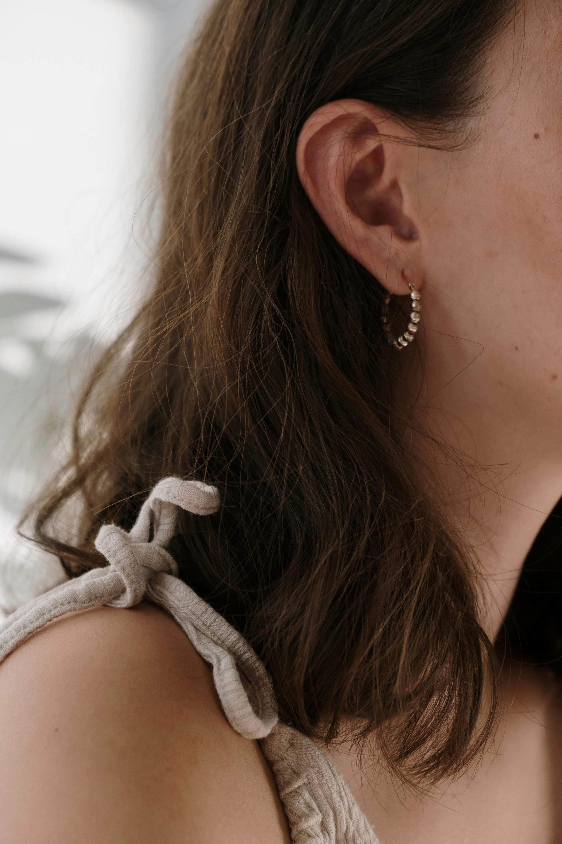 Close-up view showcasing an elegant earring on a woman with brown hair.