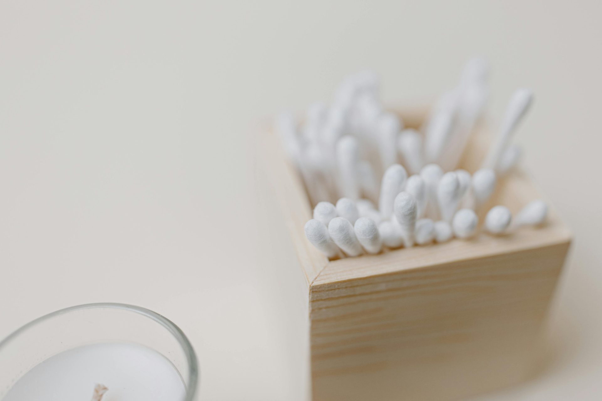 Close-up of cotton swabs in a wooden holder on a beige background; ideal for personal care themes.
